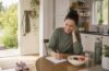 Woman planning a healthy daily routine beside breakfast, water, and walking shoes